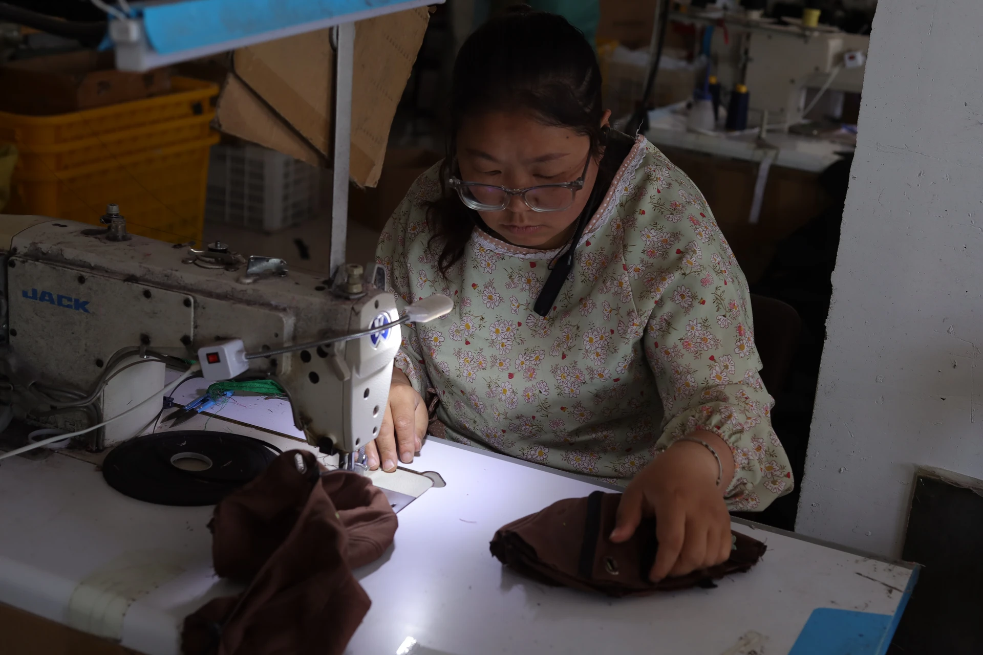 Brown cap panels being stitched at an industrial sewing machine