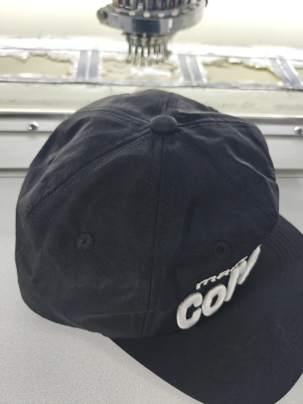 Top view of black cap showing crown seams and top button