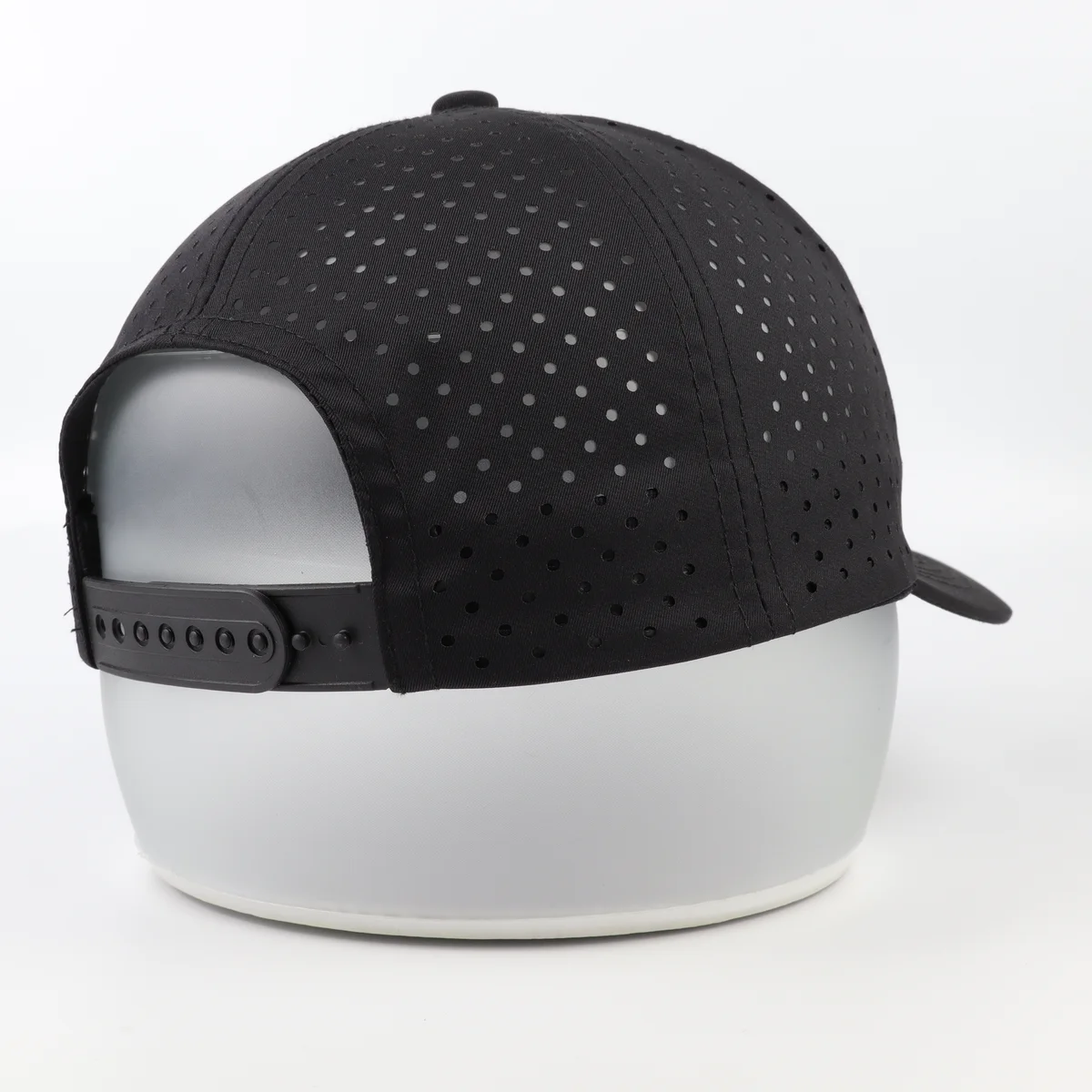 Black perforated six-panel cap photographed from the rear showing adjustable snapback and crown panels