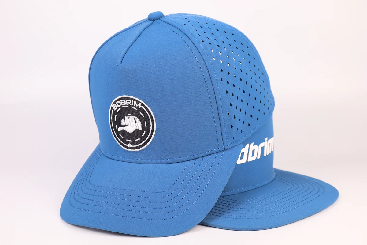 Blue custom laser-perforated golf cap showing full curved visor, front embroidered patch and perforated side crown